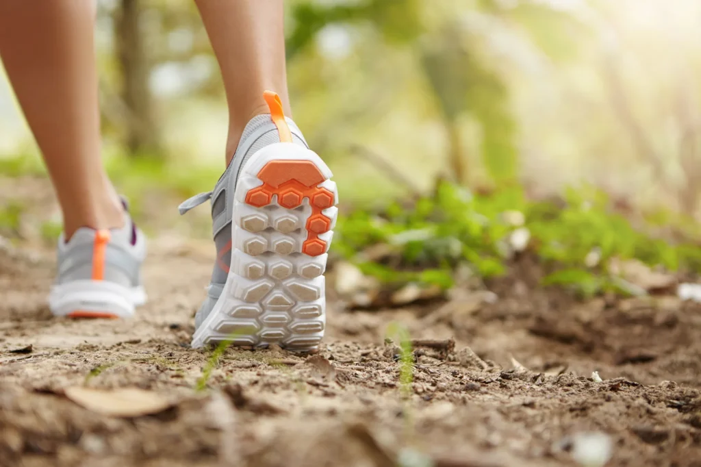 Sports fitness nature healthy lifestyle concept young female runner wearing sneakers running shoes while hiking jogging park sunny day